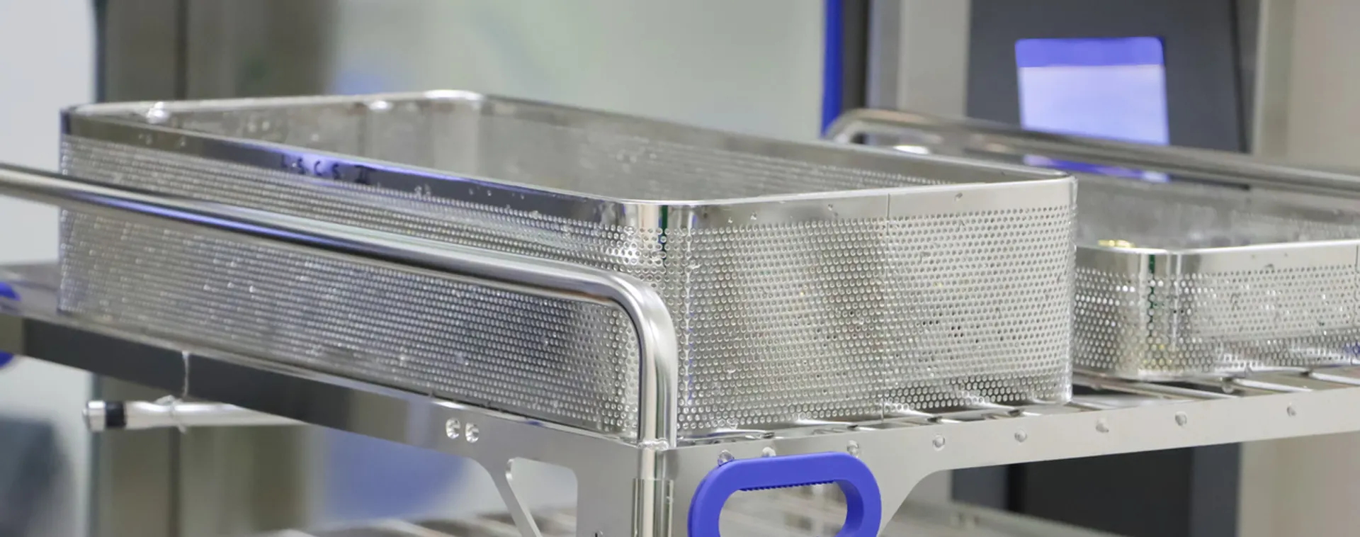 Empty stainless steel wire trays on a cart inside a medical sterilization or processing room.